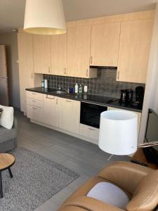 a kitchen with white cabinets and a couch and a table at Zonnig appartement in Nieuwpoort