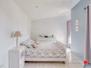 Dormitorio blanco con cama y lámpara en maison blanche piscine et petit déjeuner en Châtellerault
