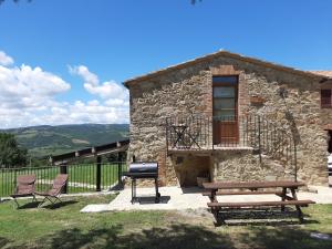 una casa de piedra con una parrilla y un banco en La Moiana 1756, en Castiglione dʼOrcia