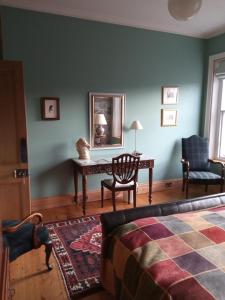 a bedroom with a table and a chair and a mirror at Kirkview House in Moffat