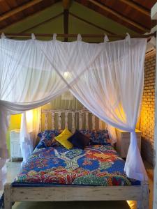 un letto a baldacchino con tende bianche di Bangalo Outeiro das Brisas a Praia do Espelho