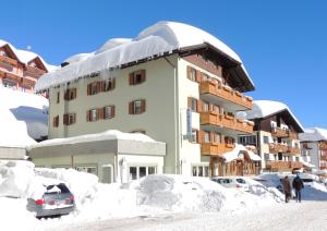 a building covered in snow with people standing in front of it at Albergo Eden in Passo del Tonale