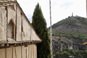 un vieux bâtiment et un pin à côté d'une colline dans l'établissement APARTAMENTO LA PONDEROSA, à Cuenca