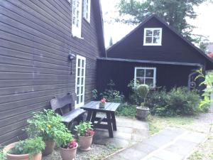 un banco frente a una casa negra con macetas en FeWo Katharina (Teestube Undeloh) Lüneburger Heide, en Undeloh