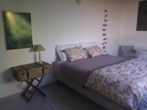 a bedroom with a bed and a side table at Un séjour privilégié à La Villa Gialla chambre d'hôte et loft dans une maison de charme avec piscine à débordement in Schœlcher
