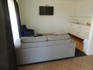 a living room with a couch and a tv at Argyle Terrace Motor Inn in Batemans Bay