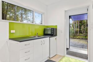 une cuisine avec un évier et un micro-ondes dans l'établissement Bellbird Cottage - Lake Taupo Bach, à Waitahanui