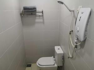 La salle de bains blanche est pourvue d'une douche et de toilettes. dans l'établissement Tropika Garden Hotel, à Johor Bahru