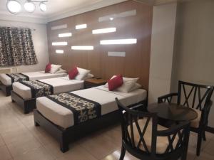 Jupiter Suites في مانيلا: سريرين في غرفة مع طاولة وكراسي