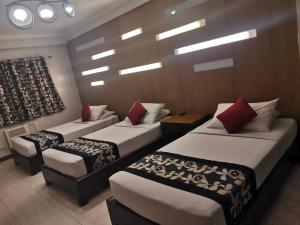 a hotel room with three beds with red pillows at Jupiter Suites in Manila