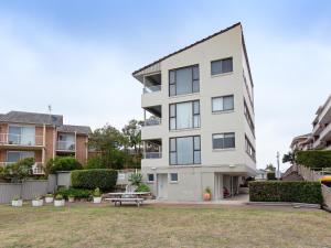 a white building with a park in front of it at Bangalee 3 Fantastic Waterfront Unit with Pool WI FI and Chromecast in Soldiers Point