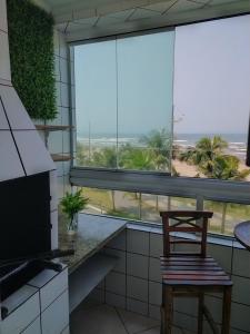 a chair in a kitchen with a view of the ocean at Apto. (pé na areia) com Churrasqueira na sacada in Praia Grande
