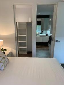a bedroom with a white bed and a kitchen at Centrepoint Units Heidelberg in Melbourne