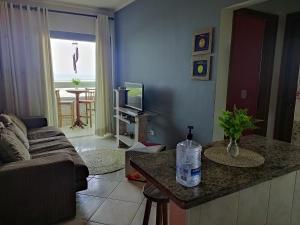 a living room with a couch and a kitchen with a table at Apto. (pé na areia) com Churrasqueira na sacada in Praia Grande