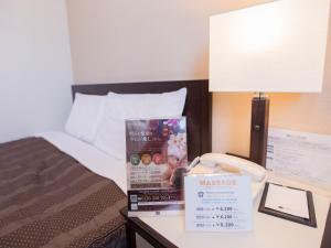 a hotel room with a bed and a sign on a table at Meitetsu Inn Nagoya Nishiki in Nagoya