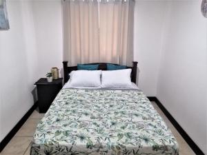 een slaapkamer met een bed met een groen en wit dekbed bij Kubo Apartment Private 2 Bedrooms 5 mins SJO Airport with AC in Alajuela