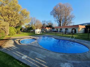 a swimming pool in a yard next to a house at Matador Motel in Carterton