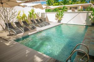 a swimming pool with chairs and an umbrella at Beachcove Apartment 2 in Pereybere