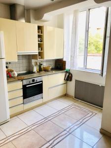a kitchen with white cabinets and a large window at La Gare Apartment in Varna City