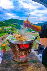 une personne qui agite un pot de nourriture sur une table dans l'établissement Phutonso Homestay, à Chiang Mai