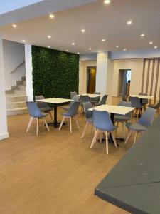 una sala de espera con mesas y sillas y una pared verde en Planet Blue Hotel, en El Arenal
