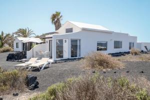 a white house with chairs in a yard at El Loft in Famara