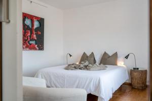 a white bedroom with a bed and a chair at El Loft in Famara