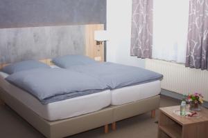 a bedroom with a bed with blue sheets and a table at Stichwehs Hotel am Bahnhof in Elze
