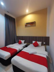 two beds in a hotel room with red pillows at Hotel Ideal Senawang in Seremban