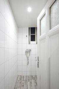 a white tiled bathroom with a shower and a door at Hostel Musala in Varna City