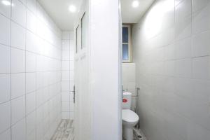 a white bathroom with a toilet and a window at Hostel Musala in Varna City