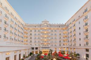 un grand bâtiment avec des parasols rouges dans la cour dans l'établissement Grand Hotel Palace, à Thessalonique