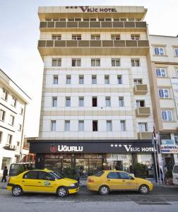 two yellow cars parked in front of a building at Kucuk Velic Hotel in Gaziantep