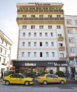 twee gele auto's geparkeerd voor een gebouw bij Kucuk Velic Hotel in Gaziantep