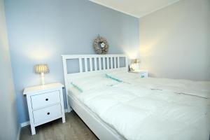 ein Schlafzimmer mit einem weißen Bett und einem weißen Nachttisch in der Unterkunft Ferienpark G11-012 Ferienpark in Heiligenhafen