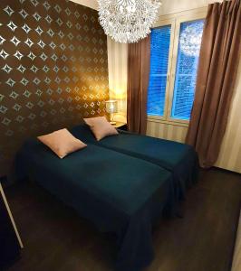 Un dormitorio con una cama azul y una lámpara de araña. en YlläStar III 606 - 2 bdrm, sauna, en Äkäslompolo