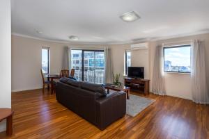 a living room with a couch and a table with a television at Perth West End Apartment 406 in Perth