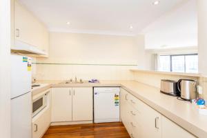 una cucina bianca con armadietti e elettrodomestici bianchi di Perth West End Apartment 406 a Perth