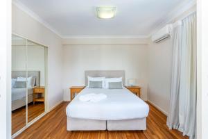 sypialnia z białym łóżkiem i lustrem w obiekcie Perth West End Apartment 406 w mieście Perth