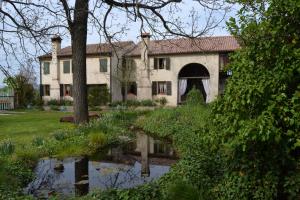 una casa vieja con un estanque delante de ella en Regina Sconta en Villa Estense