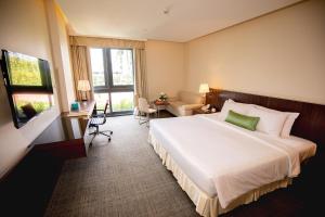 una camera d'albergo con un grande letto e una scrivania di Becamex Hotel New City a Thu Dau Mot