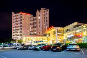 un aparcamiento con coches estacionados frente a los edificios en Becamex Hotel Thu Dau Mot, en Thu Dau Mot