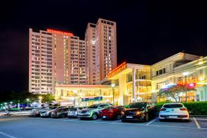 a parking lot with cars parked in front of buildings at Becamex Hotel Thu Dau Mot in Thu Dau Mot