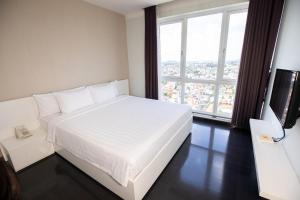 a white bed in a room with a large window at Becamex Hotel Thu Dau Mot in Thu Dau Mot