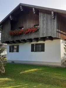 une maison avec un balcon orné de fleurs rouges. dans l'établissement Pension & Fewos Fuchs, à Mauth