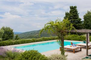 a woman sitting on a chair next to a swimming pool at Villa Il Poggio in Greve in Chianti