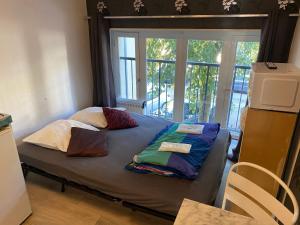 een bed met kussens in een kamer met een raam bij Les studios meublés de l'avenue Bouloumié Vittel in Vittel