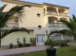 - un grand bâtiment blanc avec balcon et palmiers dans l'établissement Croliday Apartment with Pool Nin, à Vrsi