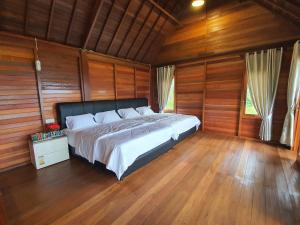 a bedroom with a bed with wooden walls and wooden floors at Flower Hill Villa Bali 'Villa Bukit Berbunga Bali' in Bedugul