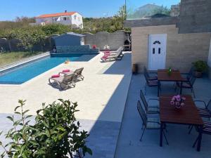 eine Terrasse mit Tischen und Stühlen neben einem Pool in der Unterkunft Apartment Maki with new Pool Nin in Vrsi